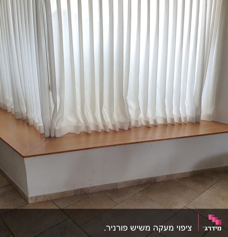 מדף עץ רחב מתחת לחלון עם וילון לבן